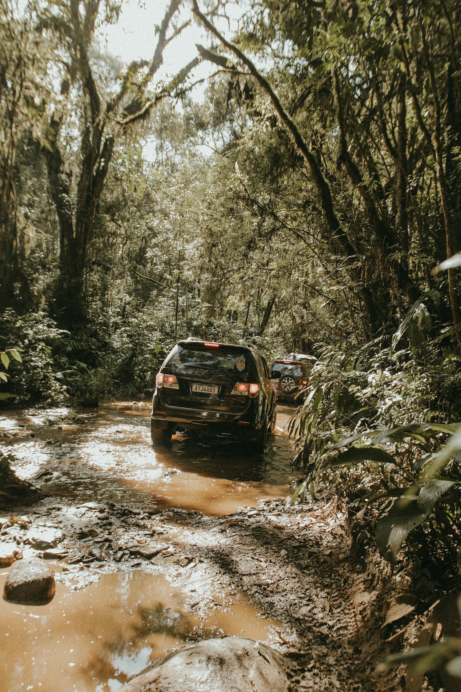 Veículo 4x4 atravessando lama em uma trilha na mata